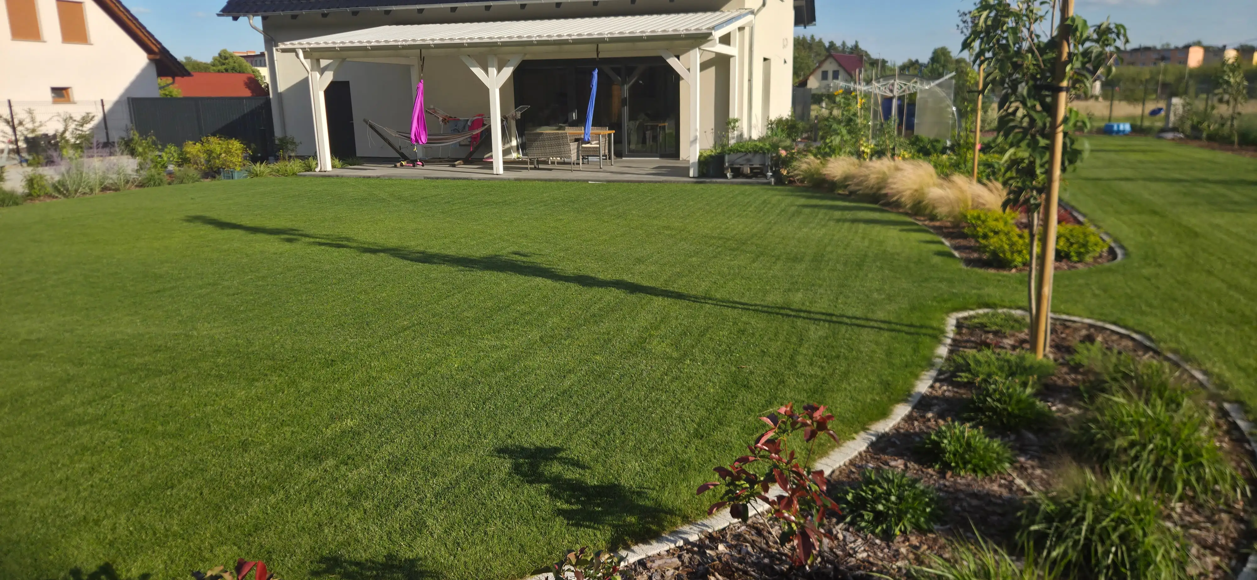 Frisch angelegter Rasen mit Pflanzbeeten und Terrasse – Realisierung von ARTEGARDENS